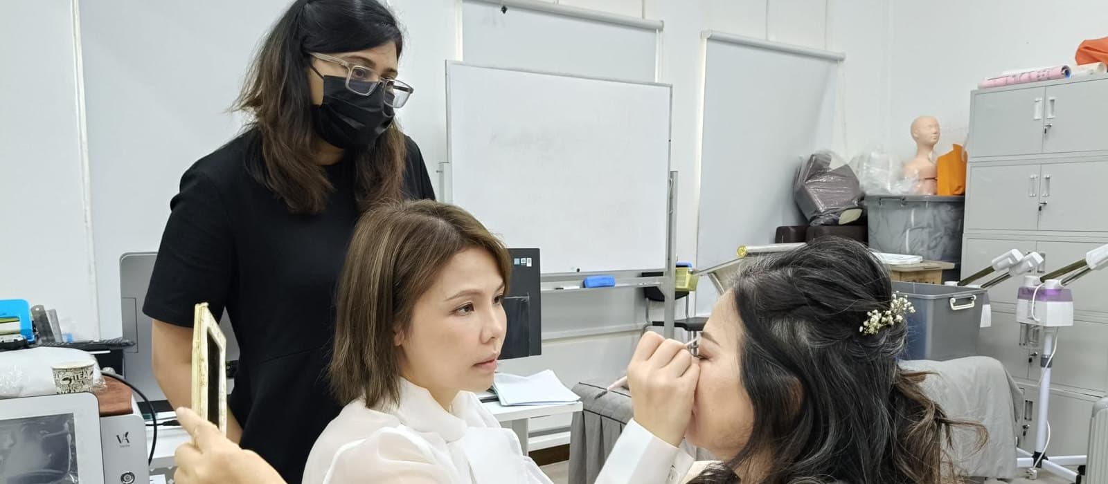 A Toni International training room: a trainee shaping a model's brows while the instructor watches